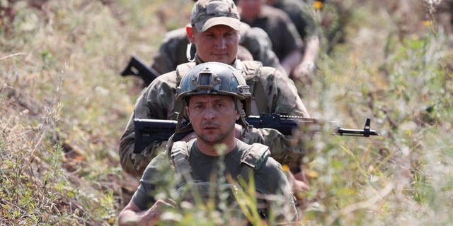 Ukraine's President Volodymyr Zelenskiy and servicemen walk in a trench near the frontline with Russian-backed separatists in Krasnohorivka in Donetsk Region, Ukraine, Aug. 7, 2020. 
