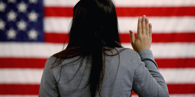 A woman takes the oath of allegiance during a naturalization ceremony at the at district office of the U.S. Citizenship and Immigration Services on Jan. 28, 2013 in Newark, New Jersey.