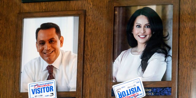 Stickers are placed on the pictures of Los Angeles Council members Gil Cedillo, left, and Nury Martinez near the entrance of the John Ferraro Council Chamber on Oct. 12, 2022, in Los Angeles. 