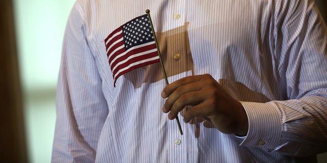 A new U.S. citizen holds the American flag during a naturalization ceremony at the Treasury Department July 3, 2013 in Washington, DC.