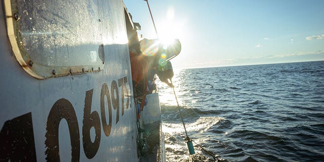 Crew members aboard a boat sailing in coastal Maine waters.